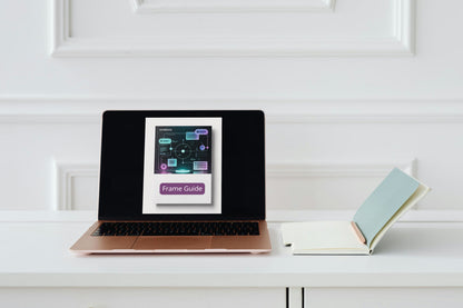 Laptop displaying a 'Frame Guide' on a white surface with a book next to it.